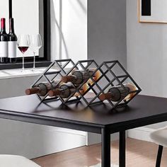 a black table with wine bottles and glasses on it in front of a mirror that is next to a white chair