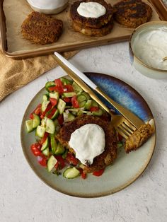 a plate with some food on it next to a bowl of yogurt and a fork