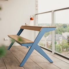 a wooden bench sitting on top of a hard wood floor next to a large window