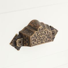 an ornate wooden door handle on a white wall