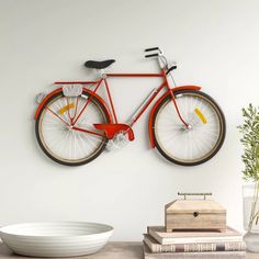 a red bike mounted to the wall next to a white bowl and vase on a table