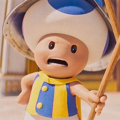 a toy figurine is holding a stick and wearing a blue and yellow outfit