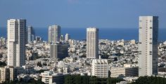 an aerial view of a city with tall buildings and the ocean in the back ground