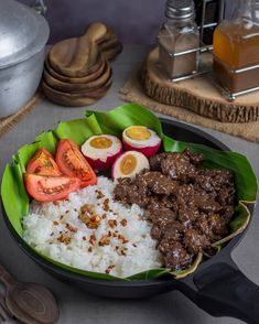 a bowl filled with rice, meat and vegetables on top of a table next to utensils