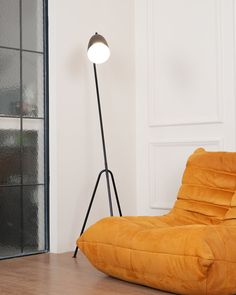 an orange bean bag chair sitting on top of a wooden floor next to a lamp