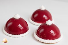 three red desserts with white frosting and santa's hats sitting on top of each other