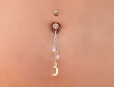 a belly button with a chain attached to it and a moon charm hanging from the side