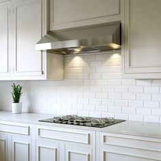 a stove top oven sitting inside of a kitchen next to white cabinets and counter tops