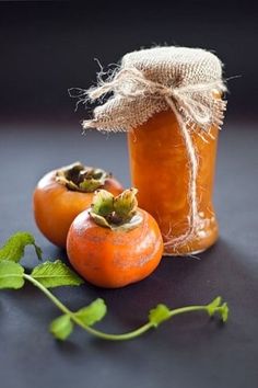 two tomatoes sitting next to a jar of honey