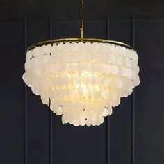 a white chandelier hanging from a ceiling with black walls and wooden flooring