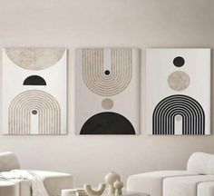 three abstract paintings hang on the wall above a white couch in a modern living room