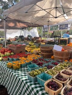 an open air market with lots of fresh fruits and vegetables on tables under a tent