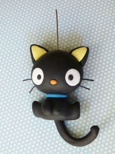 a black cat with big eyes hanging from a hook on a blue and white wall