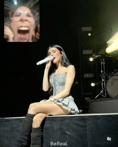 a woman sitting on top of a stage with a microphone in front of her mouth