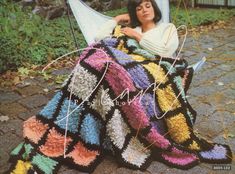 a woman laying on the ground with a crocheted blanket