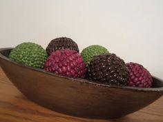 a wooden bowl filled with lots of different colored balls on top of a wood table