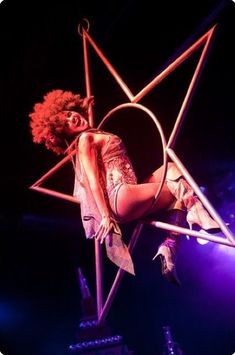 a woman is sitting on top of a pole with her legs in the air while holding onto an object