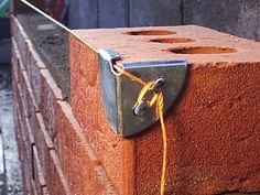 a piece of red brick tied up to a wall with yellow cord and padlocks