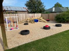 an outdoor play area with tire tires on the ground and a wooden fence in the background