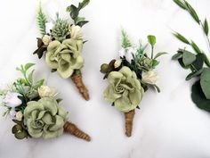 three small bouquets of flowers are arranged on a marble surface with greenery and foliage