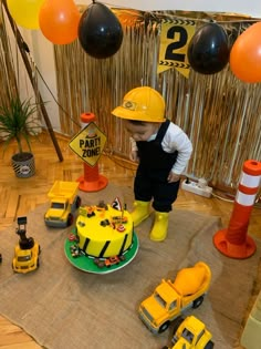 a young boy standing in front of a construction themed cake