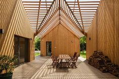 the inside of a wooden building with tables and chairs on it's patio area