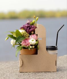 a cup holder made out of cardboard with flowers in it and a straw sticking out of the top