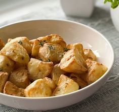 a white bowl filled with potatoes on top of a table