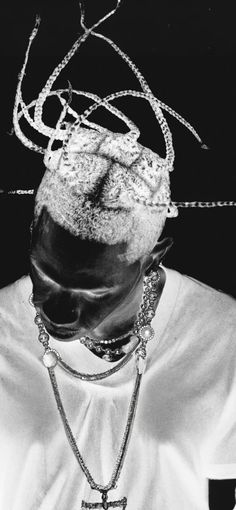 a black and white photo of a person wearing a hat with chains on it's head