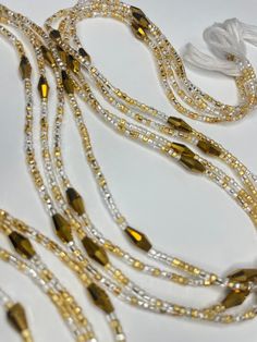 Why You'll Love It: Elegant Design: The delicate blend of gold and clear glass seed beads, highlighted by larger gold crystal glass accents, creates a timeless and refined look. High-Quality Materials: Crafted with premium glass seed beads and crystal glass accents, ensuring durability and a lasting shine. Adjustable Fit: Designed for comfort and versatility, this waist bead adjusts to fit perfectly. Versatile Style: Perfect for everyday wear, special occasions, or as a meaningful gift. Cultural Elegant Yellow Beaded Bracelets With Gold Beads, Elegant Yellow Beaded Bracelet With Gold Beads, Bohemian Gold Beaded Bracelets With Spacer Beads, Gold Beaded Bracelets With Tiny Beads For Party, Gold Necklaces With Polished Metal Beads, Gold Necklaces With Metal Beads, Gold Bohemian Beaded Bracelets For Wedding, Bohemian Gold Beaded Bracelets For Wedding, Elegant Gold Beaded Necklace With Spacer Beads