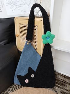 a black cat purse sitting on top of a chair next to a wall with a green flower