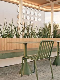 two green chairs sitting next to each other near a table and potted plant in the background