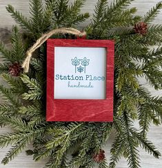 the station place christmas ornament is hanging on a tree branch with pine cones and twine