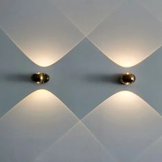 three lights that are on the side of a white wall with diamond shaped tiles behind them