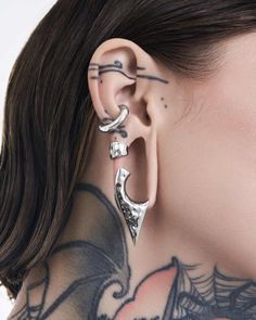 a woman with tattoos on her neck and behind the ear piercings is looking at the camera