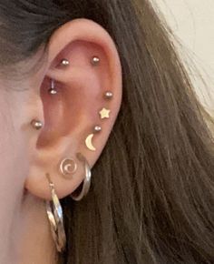 a woman wearing ear piercings with stars and moon designs on it's ears