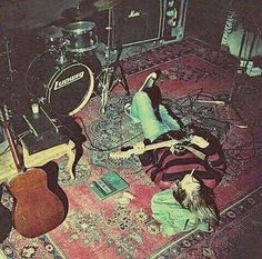 a group of people laying on top of a rug next to guitars and amps