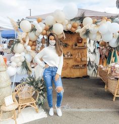 a woman standing in front of a table with white balloons and other items on it