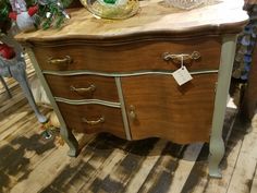 an old dresser with a glass bowl on top and christmas tree in the back ground