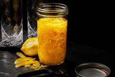 a glass jar filled with yellow liquid next to some sliced bananas and other food items