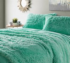 a bed with a green comforter and pillows