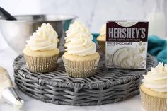 cupcakes with white frosting and a carton of hershey's