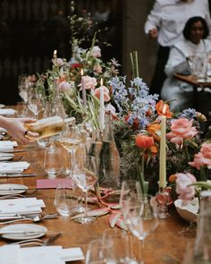 a long table is set with wine glasses and flowers