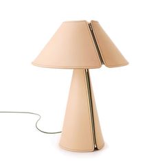 a beige lamp with a white shade on the side and a cord connected to it