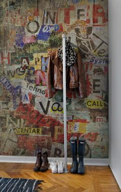 a pair of boots and jacket hang on a coat rack in front of a wall covered with posters