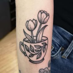 a black and white tattoo with flowers in a cup