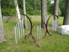 several metal sculptures in the grass near trees