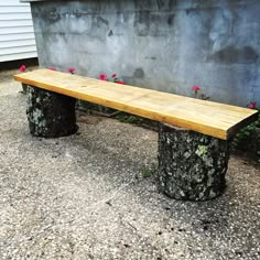 a wooden bench sitting in front of a cement wall with flowers growing on the side