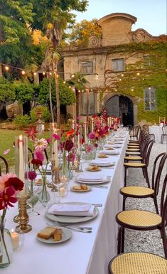 a long table is set up with flowers and candles for an outdoor dinner or party