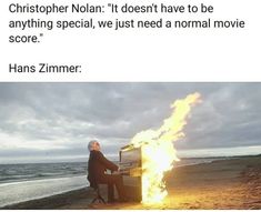 a man sitting in front of a fire on top of a beach next to the ocean